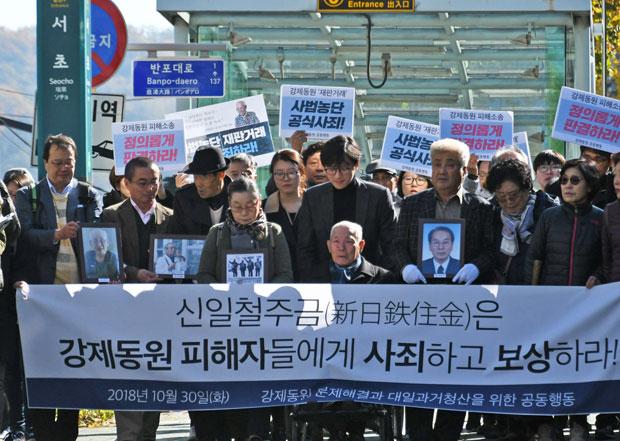 故人となった元徴用工の遺影を掲げて2018年10月30日、韓国大法院へ向かう原告たち。この日の判決では、新日鉄住金に元徴用工4人への賠償が命じられた　（ｃ）朝日新聞社